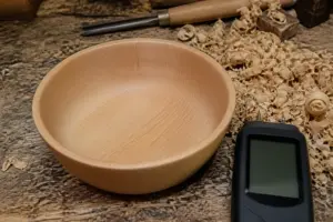 Frisch gedrechselte Schale aus Buchenholz neben Holzspaenen und einem Feuchtemessgeraet